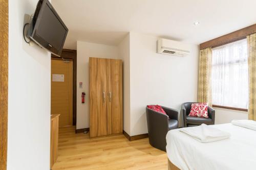 a room with a bed and a tv on a wall at Brick Lane Hotel in London
