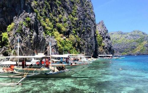 a group of boats in the water near a mountain at Bayview Country Inn El Nido in El Nido