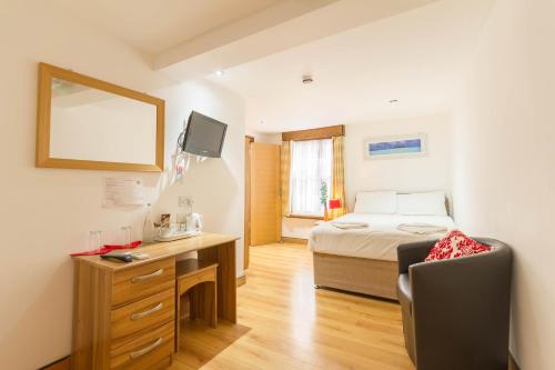 a bedroom with a bed and a desk with a chair at Brick Lane Hotel in London