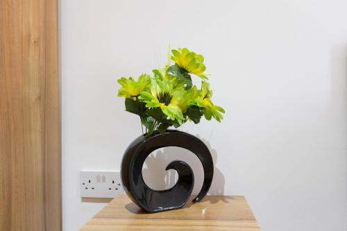 a black vase with flowers in it on a table at Brick Lane Hotel in London