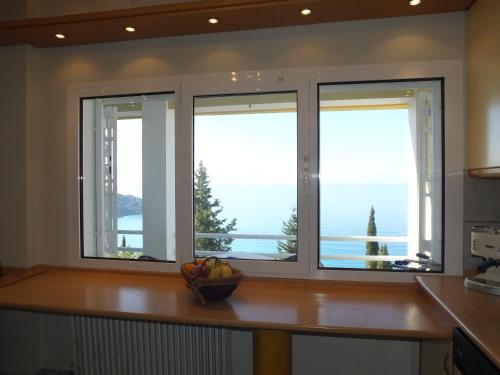 a kitchen with three windows and a bowl of fruit on a counter at Villa Alibertini in Agios Gordios