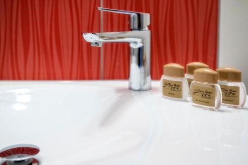 a bathroom sink with three bottles of soap next to a faucet at Hotel Eco Tatry Holiday& Spa in Kościelisko