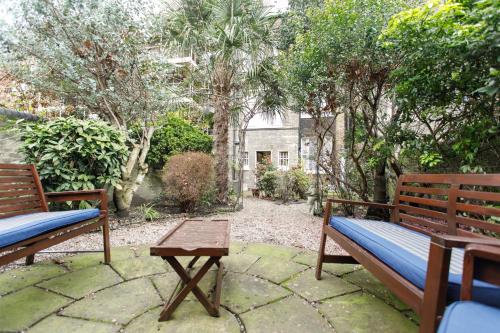 a patio with two benches and a table and trees at Jesmond Hotel in London