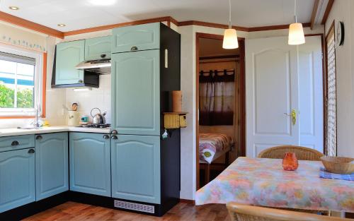 a kitchen with blue cabinets and a table at Chalet Ketjil in Oostvoorne