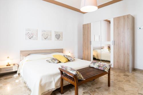 a bedroom with a white bed and a wooden bench at Casa Berta, a due passi dal mare in Numana