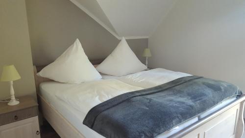 a bed with two white pillows and a blue blanket at Grüner Wald in Burg Kauper