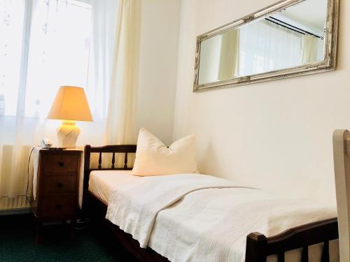 a bedroom with a bed with a mirror and a lamp at Hotel Mariahilf München in Munich