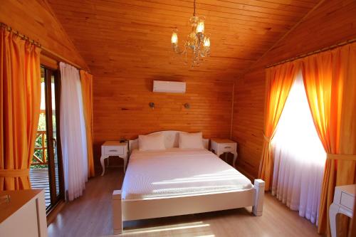 a bedroom with a white bed in a wooden room at Bahçe Villa in Cıralı