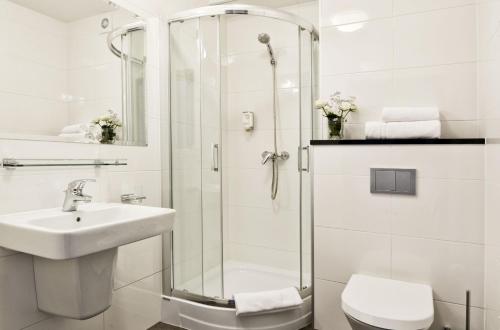 een badkamer met een douche, een wastafel en een toilet bij Hotel Port 110 in Iława