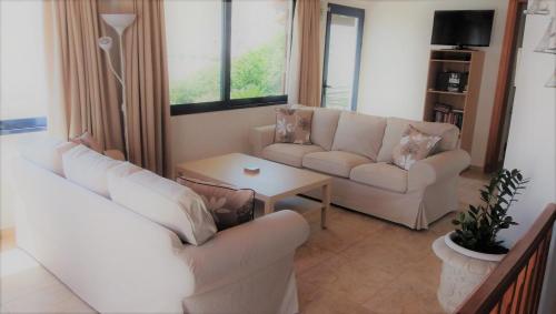 una sala de estar con 2 sofás blancos y una mesa. en Seashell en Líndos