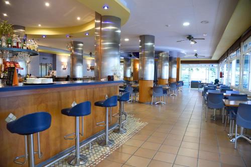 a restaurant with a bar with blue stools at Hotel Internacional in Calella