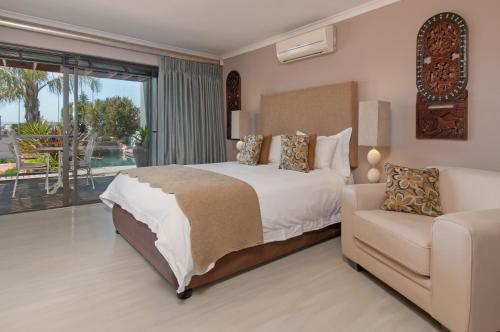 a bedroom with a bed and a couch at Whale Away Guest House in Hermanus