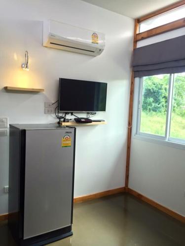 a room with a refrigerator and a flat screen tv at Baan Boom Boxes Eco Friendly Resort in Mae Nam