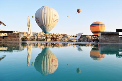 three hot air balloons flying over a pool of water at Kelebek Special Cave Hotel & Spa in Göreme