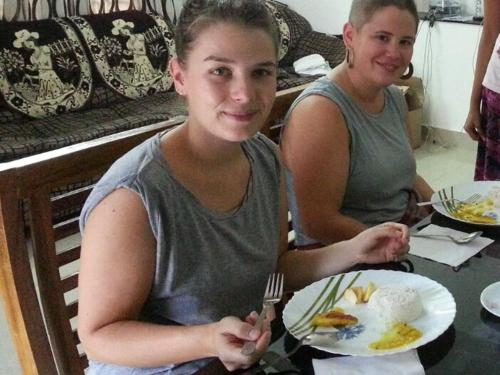 two girls sitting at a table with a plate of food at El Casa Homestay in Cochin