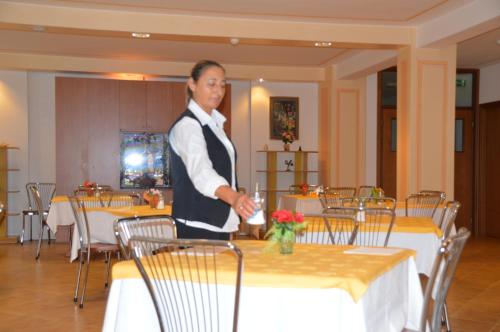 a woman standing next to a table in a restaurant at Casa Religiosa Di Ospitalità Nazareno in Spoleto