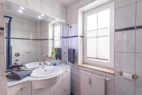 baño blanco con lavabo y ventana en Villa Mona Lisa - Ferienzimmer 8, en Göhren
