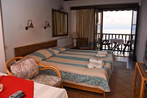 a hotel room with a bed and a chair and a balcony at Maistrali Hotel in Afissos