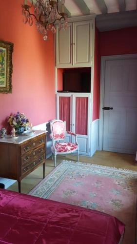 Cette chambre comprend une chaise, une commode et une porte. dans l'établissement Château de La Sémondière, à Brécey