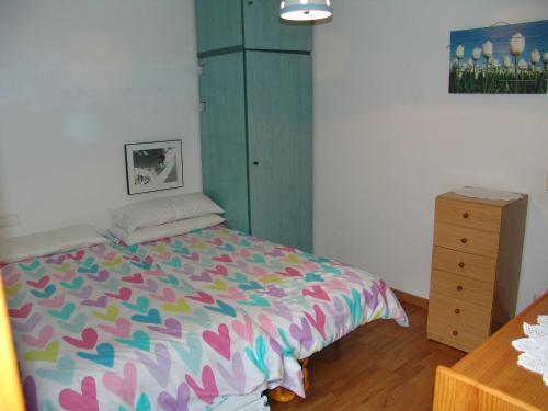 a bedroom with a colorful bed and a dresser at Apartamento en Sallent de Gallego in Sallent de Gállego