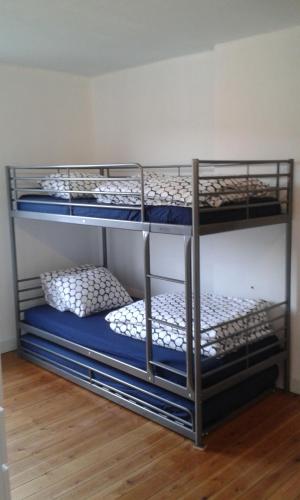 three bunk beds in a room with blue and white pillows at La petite maison in Aywaille