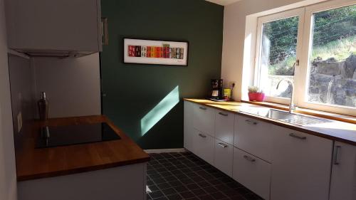 a kitchen with white cabinets and a sink and a window at La petite maison in Aywaille