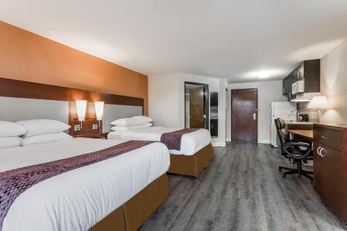 a hotel room with two beds and a desk at Days Inn & Suites by Wyndham Rocky Mount Golden East in Rocky Mount
