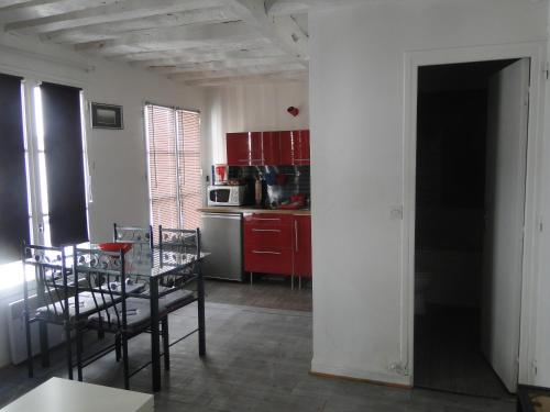 une cuisine avec des armoires rouges et une table et des chaises dans l'établissement Apartment Notre Dame, à Paris