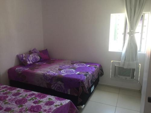 1 dormitorio con cama morada y ventana en Apartamento San Lorenzo, en Maceió