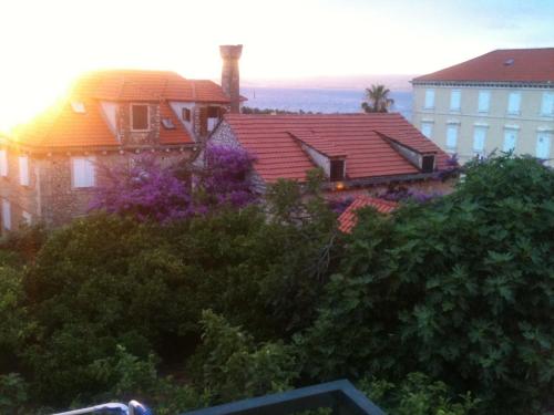 a house with a red roof and purple flowers at Apartmani Neva Supetar in Supetar