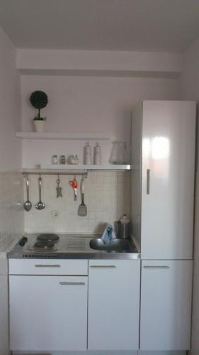 a kitchen with a white refrigerator and a sink at Apartmani Neva Supetar in Supetar