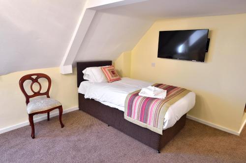 a small bedroom with a bed and a chair at The Royal Victoria and Bull Hotel in Dartford