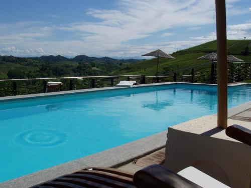 a large blue swimming pool with mountains in the background at Villa Tiboldi in Canale