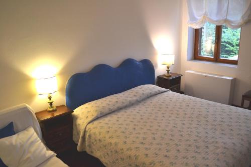 a bedroom with a bed with a blue headboard and two lamps at Villa Rilke Duino in Duino