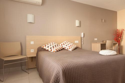 een slaapkamer met een bed met 2 kussens erop bij Logis Hotel Restaurant Le Flamant Rose camargue in Albaron