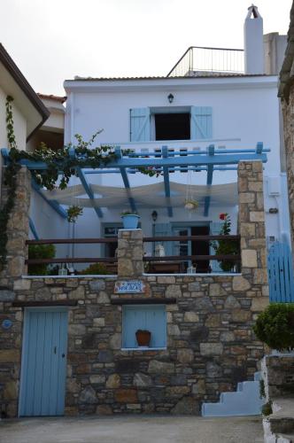 a house with a stone wall and a balcony at Stella's traditional house. in Alonnisos Old Town