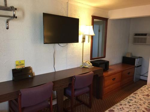 Habitación de hotel con escritorio y TV en la pared en Economy Inn Bloomington, en Bloomington