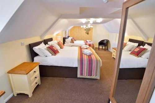 a bedroom with two beds and a mirror at The Royal Victoria and Bull Hotel in Dartford