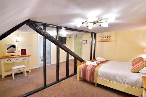 a bedroom with a bed and a desk with a tv at The Royal Victoria and Bull Hotel in Dartford