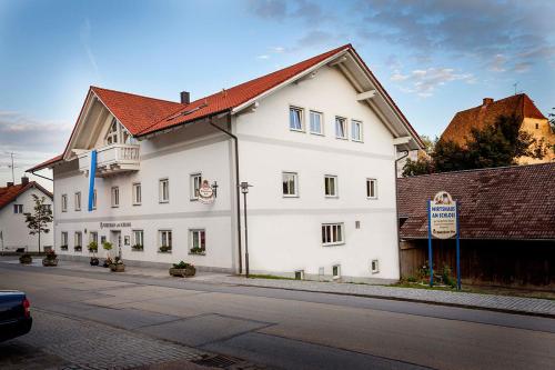 un bâtiment blanc avec un toit rouge dans une rue dans l'établissement Hotel Wirtshaus am Schloss, à Aicha vorm Wald