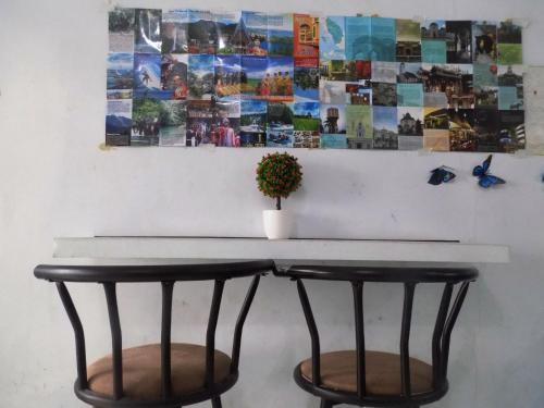 una mesa con dos sillas y una planta en una pared en Amelia 2 Guest House Syariah, en Medan