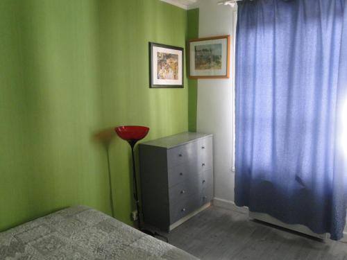 - une chambre avec des murs verts, un lit et une commode dans l'établissement Apartment Notre Dame, à Paris