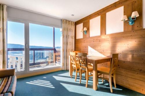 - une salle à manger avec une table, des chaises et de grandes fenêtres dans l'établissement Residence Le Pedrou - maeva Home, à Font-Romeu-Odeillo-Via