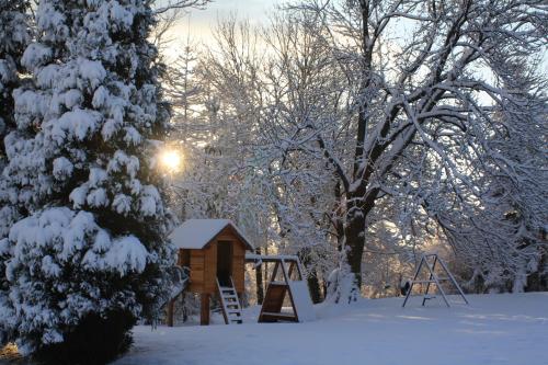 a snow covered park with a playground and a tree at Dom na Klonowym Wzgórzu in Stronie Śląskie