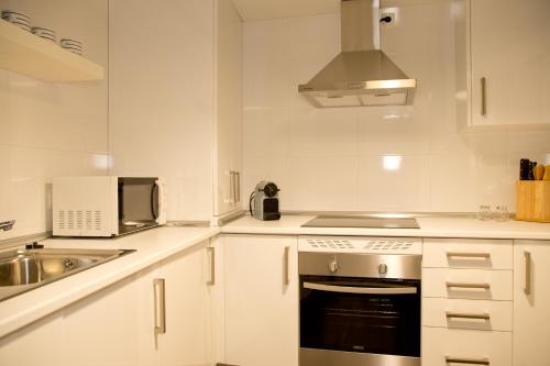 a white kitchen with a sink and a stove at Elements Rooms in Toledo