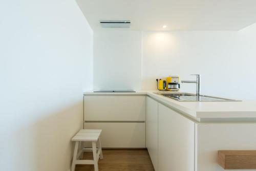 a kitchen with white cabinets and a stool in it at Apartment Sea View in Middelkerke