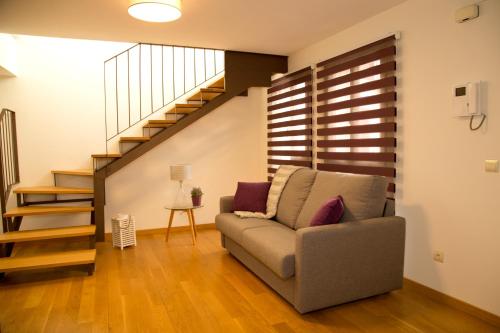 a living room with a couch and a staircase at Elements Rooms in Toledo