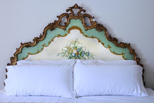a bed with an ornate headboard and white pillows at Hotel Villa Luppis in Pasiano di Pordenone