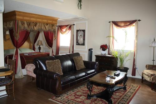 a living room with a leather couch and a bed at Woodrow House Bed & Breakfast in Lubbock