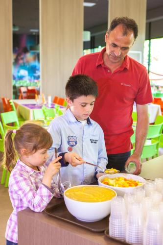 a man and two children preparing food at a table at Hôtel du Futuroscope in Jaunay-Marigny
